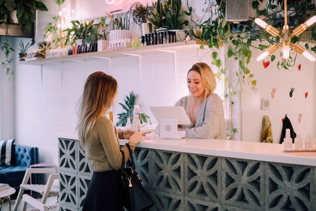 A woman paying at a counter in a plant-filled shop with a smiling clerk