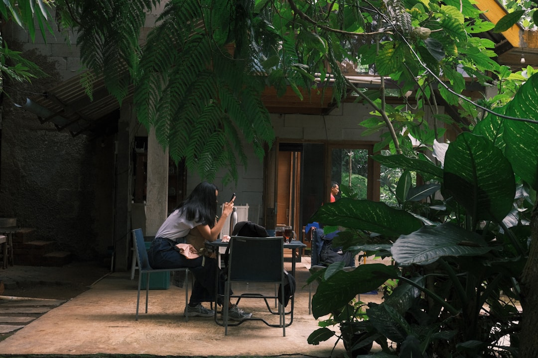 People sitting at tables in a lush, shaded outdoor cafe