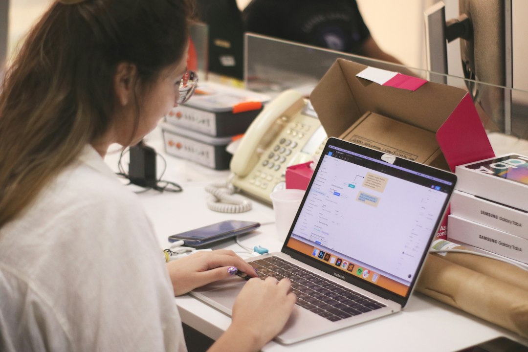 ノートパソコンでネットショップの管理画面を開き、横に商品の段ボールが積まれた作業机