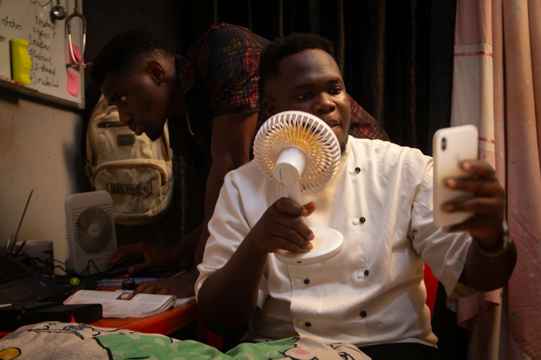 Man holds fan while taking selfie with phone