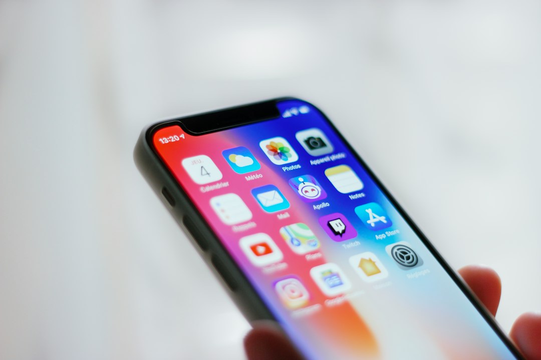 スマートフォンのホーム画面に並んだアプリのアイコンを指で操作している手元