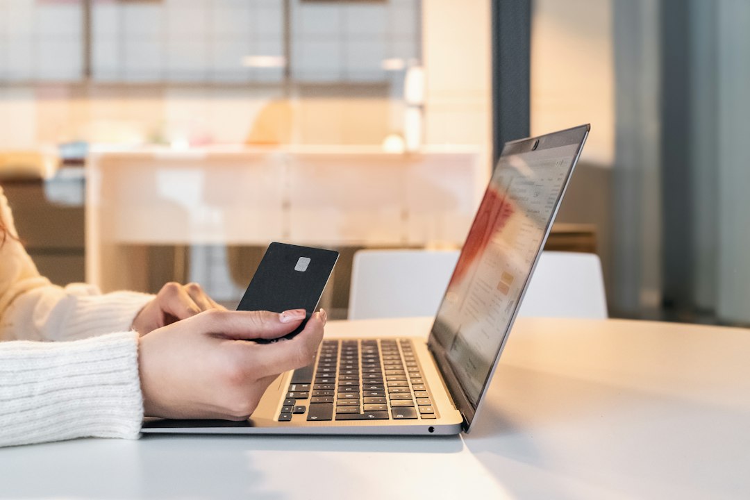 クレジットカードとスマートフォンでネット通販の支払いをする手元