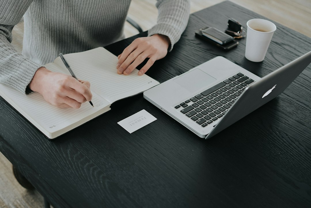 英語と日本語の資料を並べて見比べながらパソコンで作業する翻訳者